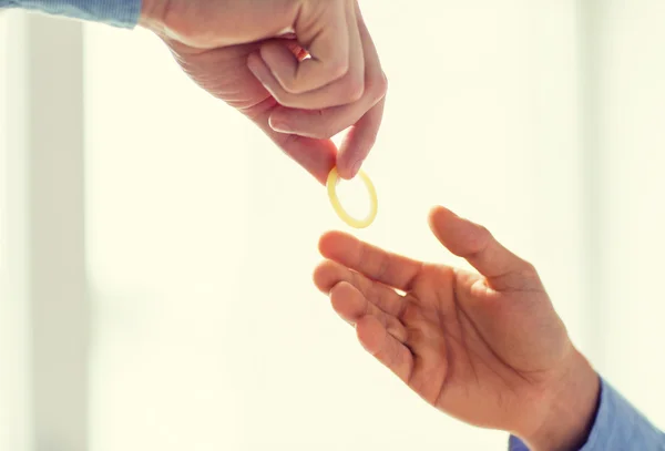 Close up of male gay couple hands giving condom — Stock Photo, Image