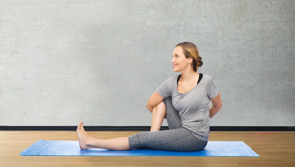 Женщина делает yoga в твист позе на циновке — стоковое фото