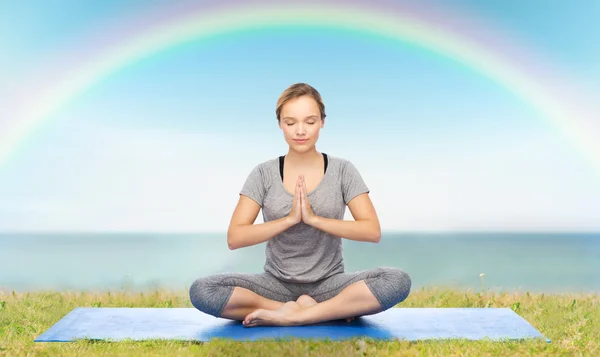 Mujer haciendo meditación de yoga en pose de loto en la estera —  Fotos de Stock