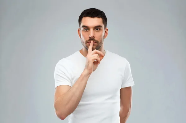 Junger Mann macht Schweigezeichen vor grauem Hintergrund — Stockfoto