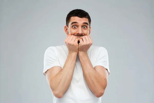 Hombre asustado en camiseta blanca sobre fondo gris —  Fotos de Stock