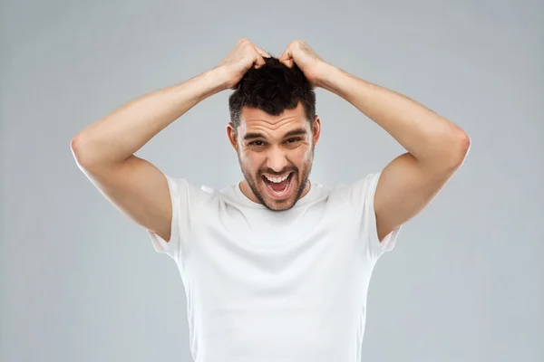 Louco gritando homem em t-shirt sobre fundo cinza — Fotografia de Stock