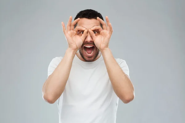 Homme faire des lunettes de doigt sur fond gris — Photo