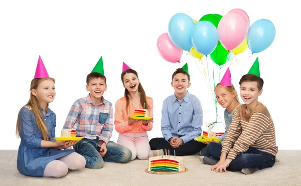 Niños felices en sombreros de fiesta con pastel de cumpleaños —  Fotos de Stock