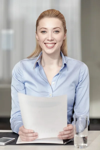 Усміхнена жінка тримає папери в офісі — стокове фото