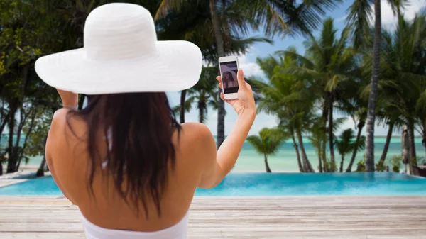Женщина делает селфи со смартфоном на пляже — стоковое фото