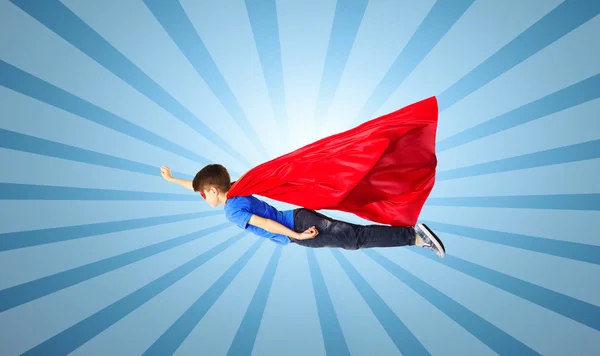 Junge in rotem Superhelden-Umhang und Maske fliegt in die Luft — Stockfoto