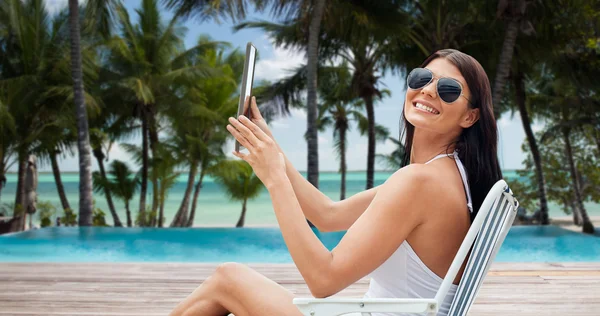 Femme souriante avec tablette pc bronzage sur la plage — Photo