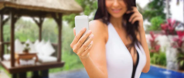 Woman taking selfie with smartphone over bungalow — Stock Photo, Image