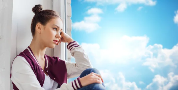 Triste chica adolescente bonita sentada en el alféizar de la ventana — Foto de Stock