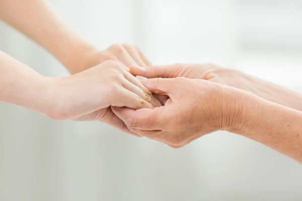 Primer plano de la mujer mayor y joven tomados de la mano — Foto de Stock