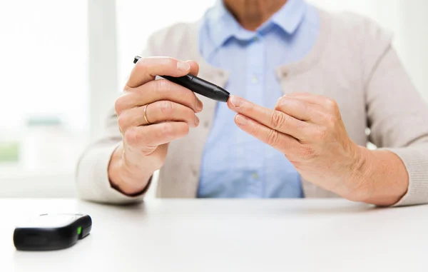 Senior woman with glucometer checking blood sugar — Stock Photo, Image