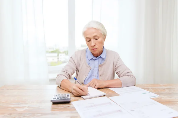 Donna anziana con carte e calcolatrice a casa — Foto Stock