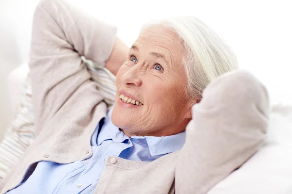 Щаслива старша жінка відпочиває на дивані вдома — стокове фото