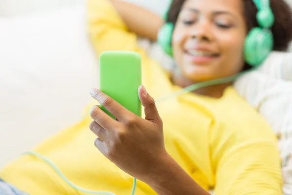 Mujer africana feliz con teléfono inteligente y auriculares —  Fotos de Stock