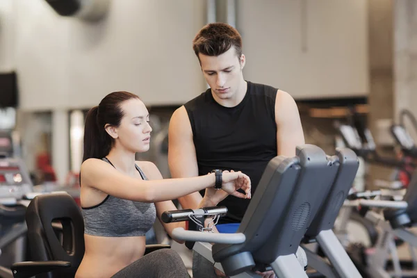 Eğitmen spor salonunda egzersiz bisikleti üzerinde kadınla — Stok fotoğraf