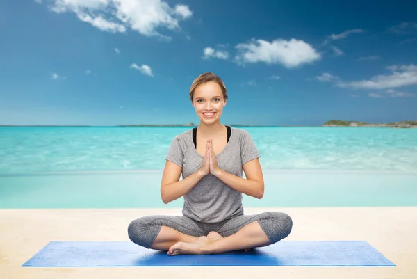Mujer haciendo meditación de yoga en pose de loto en la estera —  Fotos de Stock