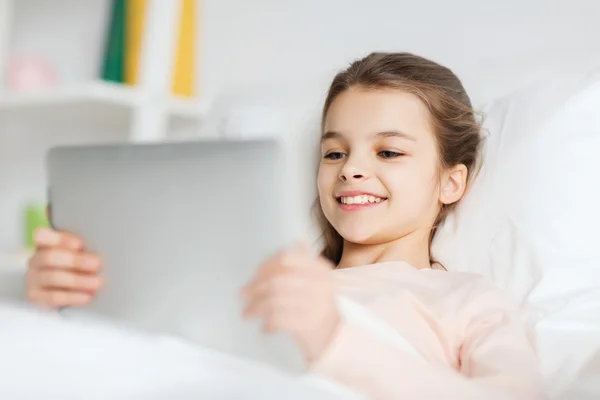 Mutlu kız evde tablet pc ile yatakta yalan — Stok fotoğraf