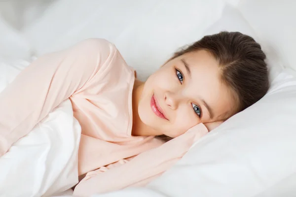 Menina sorridente feliz deitado acordado na cama em casa — Fotografia de Stock