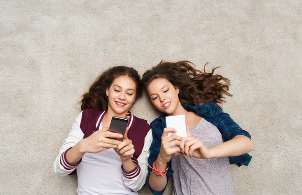 Gelukkig tienermeisjes, liggend op de vloer met smartphone — Stockfoto