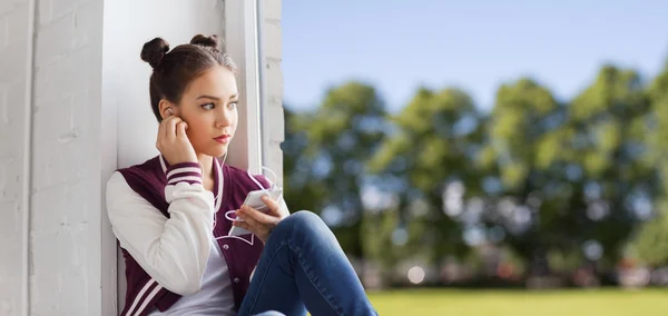 Tonårstjej med smartphone och hörlurar — Stockfoto