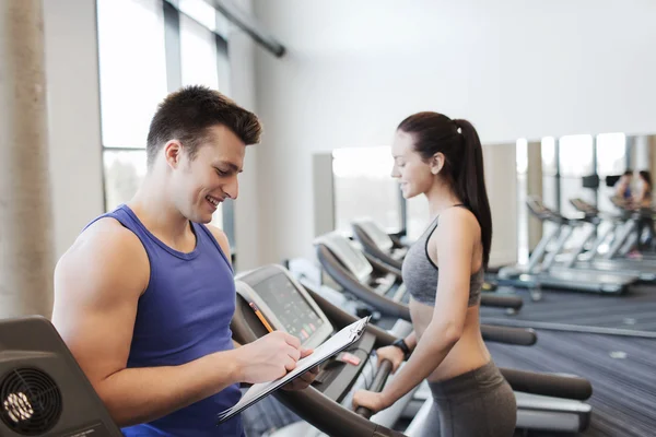 Femme heureuse avec entraîneur sur tapis roulant dans la salle de gym — Photo