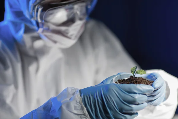 Close up of scientist with plant and soil in lab — Stock Photo, Image