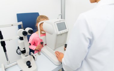 optician with autorefractor and kid at eye clinic clipart