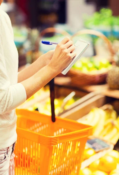 Close up of woman writing to notepad in market — Stock Photo, Image