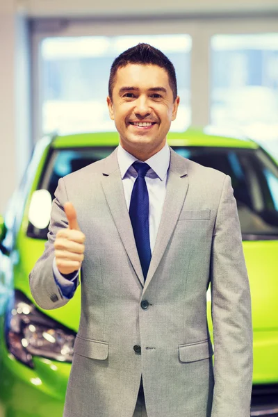 Hombre mostrando pulgares hacia arriba en el auto show o salón de coches —  Fotos de Stock