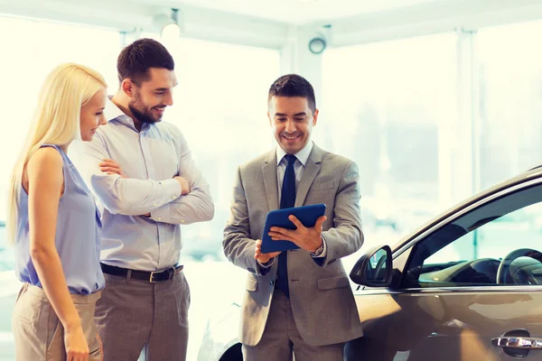 Glückliches Paar mit Autohändler in Auto-Show oder Salon — Stockfoto