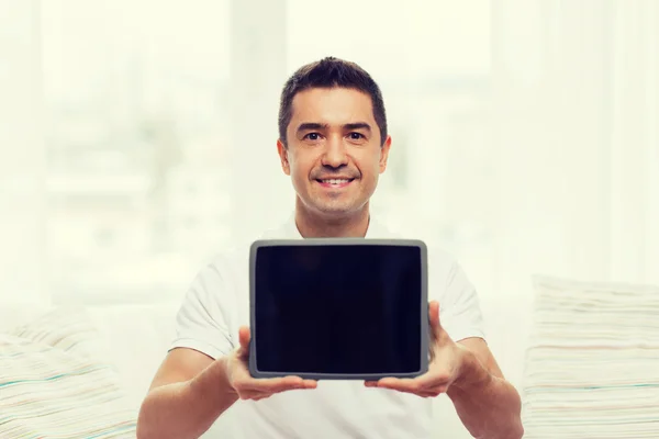 Smiling man showing tablet pc blank screen at home — Stockfoto