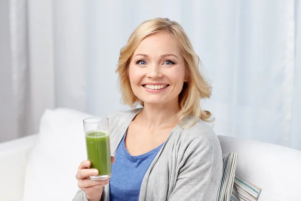 Счастливая женщина пьет зеленый сок или встряхивается дома — стоковое фото