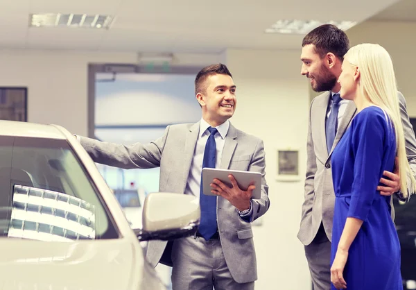 Šťastný pár s prodejci aut v autosalonu nebo salónek — Stock fotografie