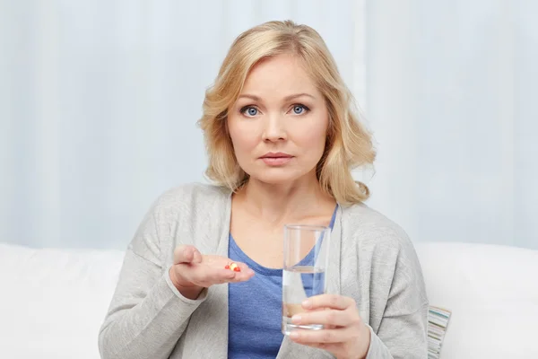 Kvinna med medicin och vatten glas hemma — Stockfoto