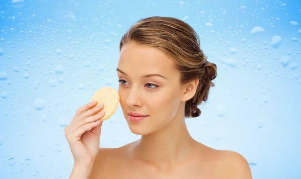 Ung kvinna rengöring ansikte med exfolierande svamp — Stockfoto