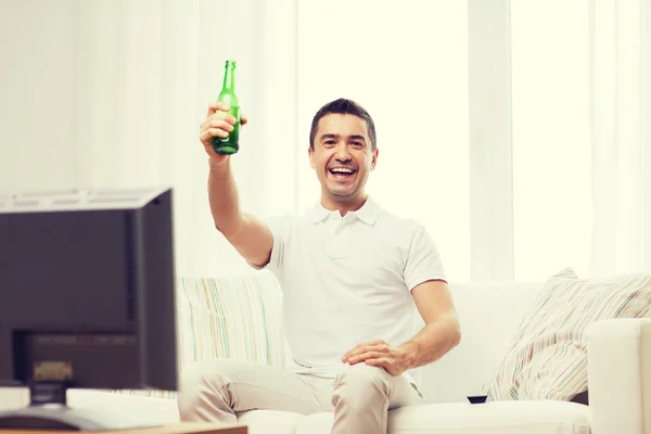 笑みを浮かべて男テレビを見て、家でビールを飲む — ストック写真