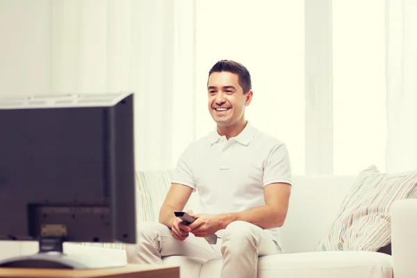 Sonriente hombre con control remoto viendo la televisión —  Fotos de Stock