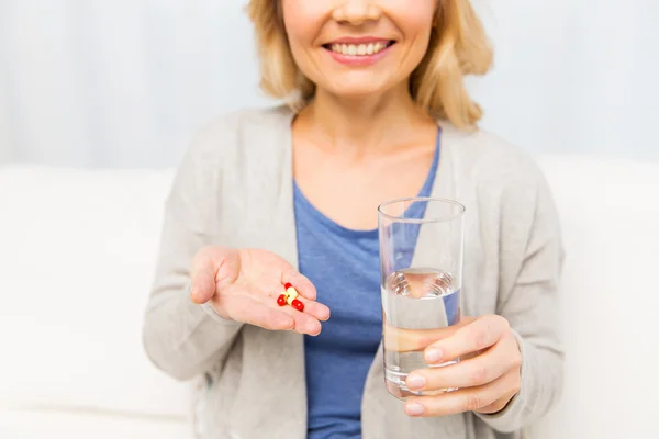 Close up of woman with medicine and water glass — Stock Photo, Image