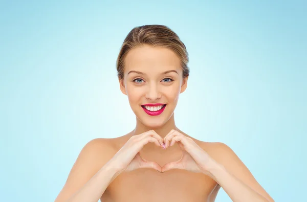 Sorrindo jovem mulher mostrando sinal de mão forma de coração — Fotografia de Stock