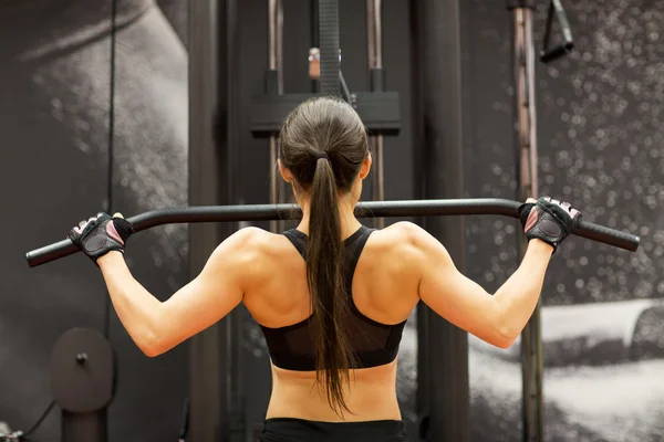 Kvinna som flexar muskler på kabel maskin i gymmet — Stockfoto