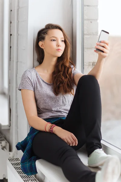 Sad pretty teenage girl with smartphone texting — Stock Photo, Image