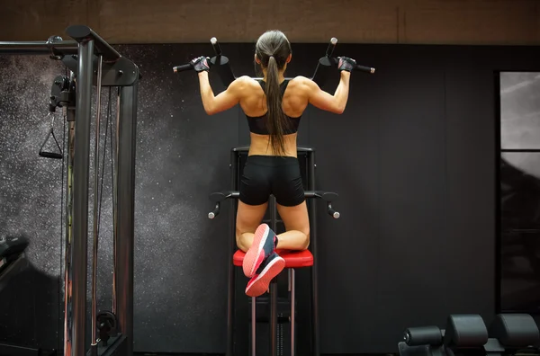 Mulher exercitando e fazendo pull-ups no ginásio — Fotografia de Stock