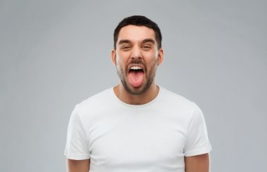 man showing his tongue over gray background clipart