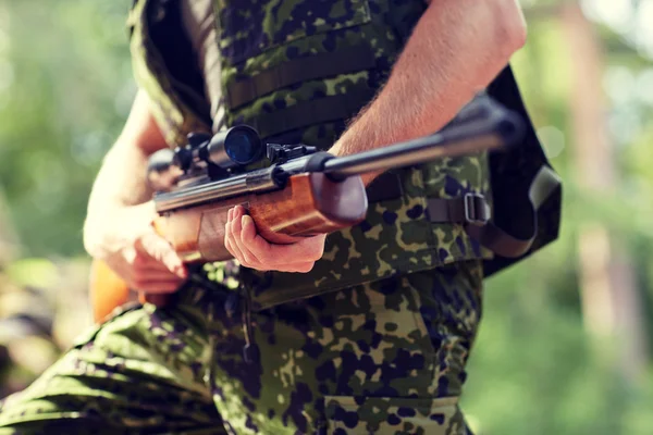 Close up of soldier or hunter with gun in forest — Stock Photo, Image