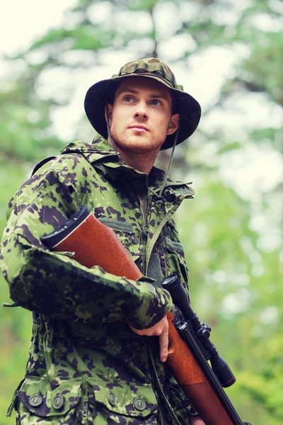 Young soldier or hunter with gun in forest — Stock Photo, Image