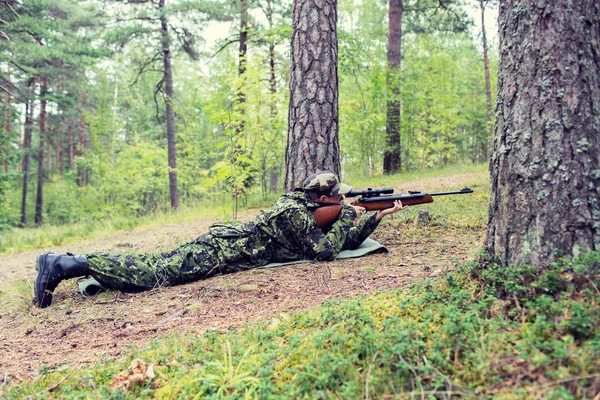 Young soldier or hunter with gun in forest — Stock Photo, Image