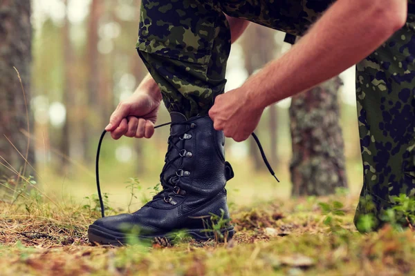 Zblízka vojáka vázání tkaničky do bot v lese — Stock fotografie