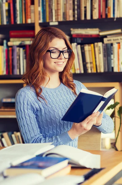 Lycklig student tjej läsa bok i biblioteket — Stockfoto