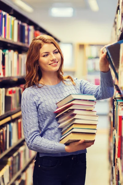 Chica estudiante feliz o mujer con libros en la biblioteca —  Fotos de Stock